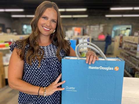 A smiling woman with a Hunter Douglas branded bag